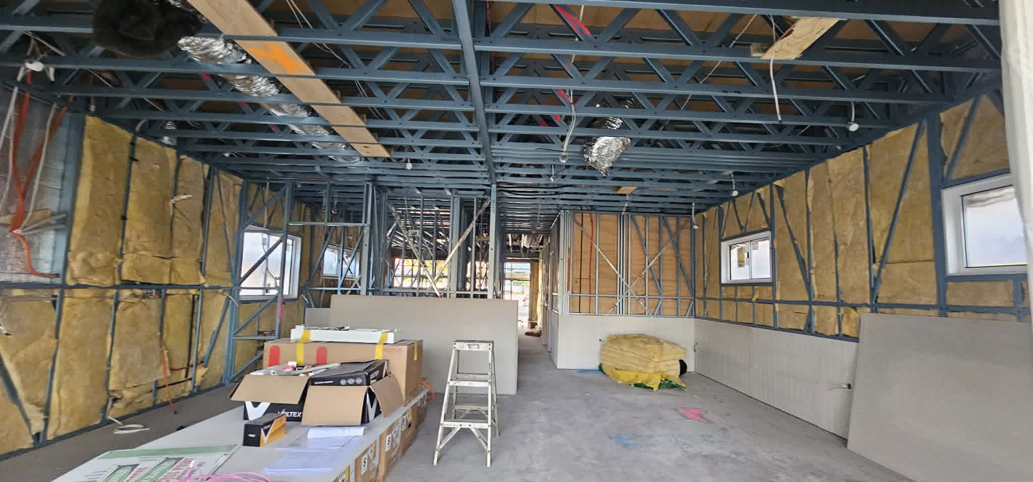 Steel-framed building fitout with insulation in the walls and electrical rough-in underway