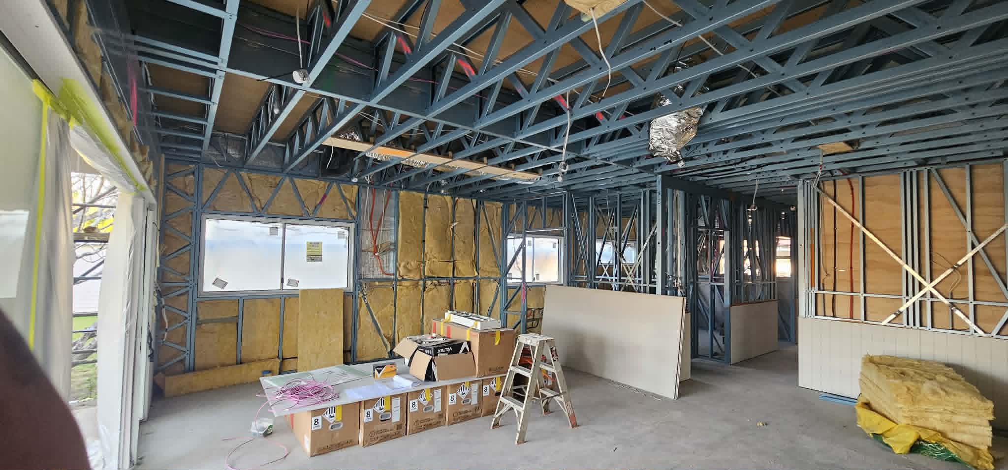 Wide view of a steel-framed fitout with ceiling battens and wiring rough-in