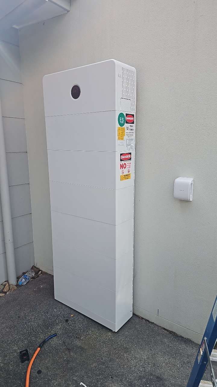 Modular home battery mounted on an outside wall with energy storage safety signage